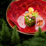 Plato gourmet con decoración vegetal en bol rojo, ambientado entre un bosque.